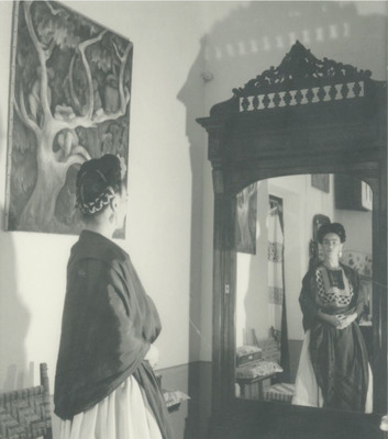 Frida Kahlo standing in front of the wardrobe mirror