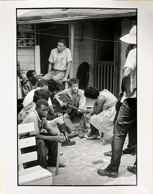 After giving a concert in a cotton field in Greenwood, Mississippi, Bob Dylan plays behind the SNCC office.